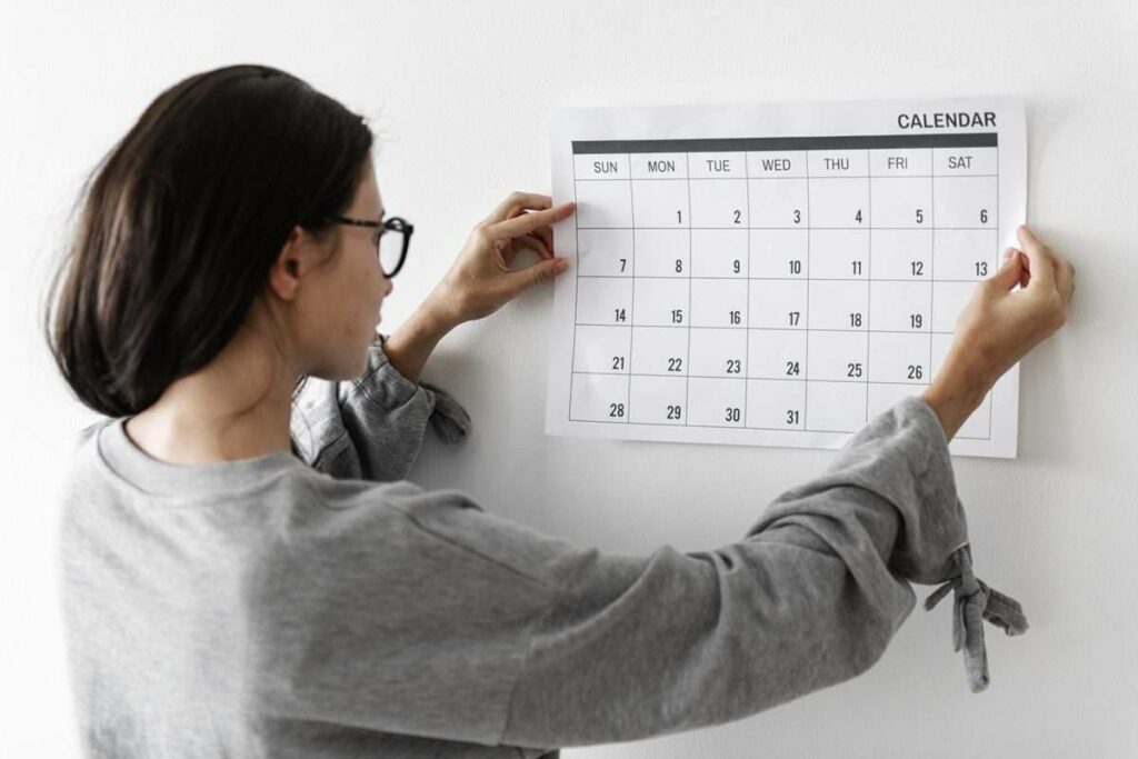 Uma mulher está segurando um calendário na parede.